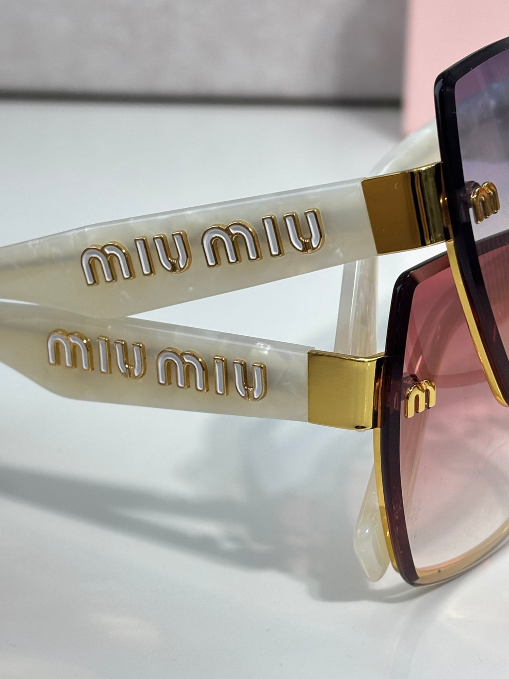 MiuMiu cat-eye sunglasses close-up of gold “miu miu” logo arms and tinted lenses