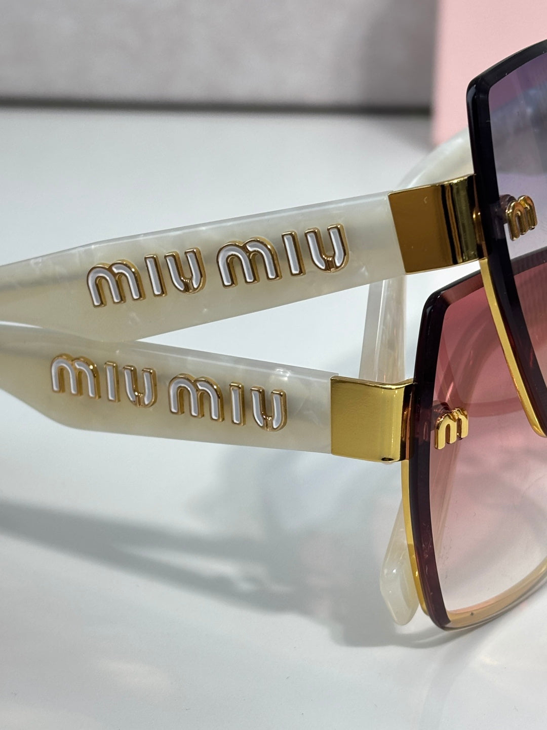 MiuMiu cat-eye sunglasses close-up of gold “miu miu” logo arms and tinted lenses
