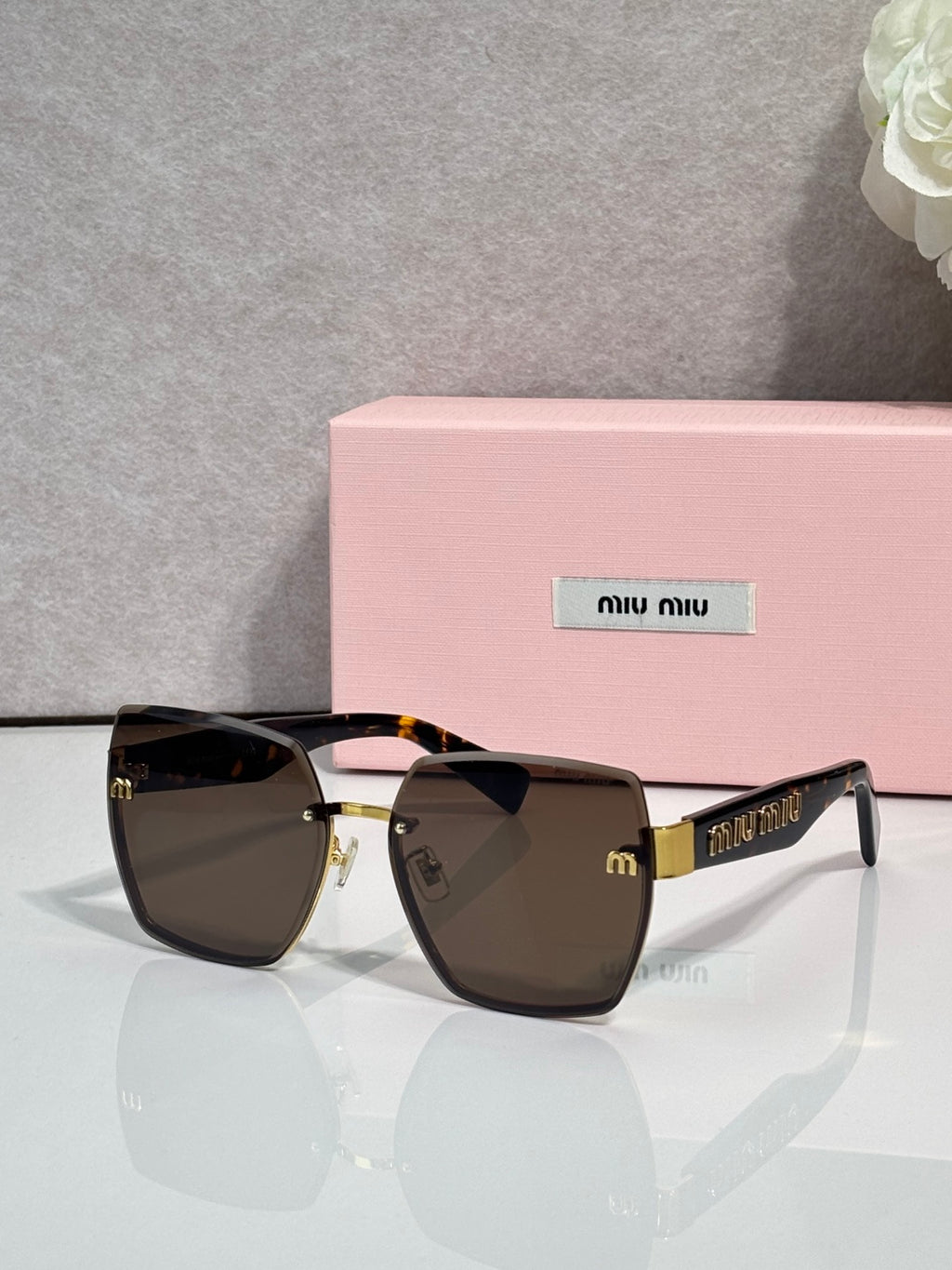 MiuMiu cat-eye sunglasses with dark lenses and gold-tone metal frame, front view