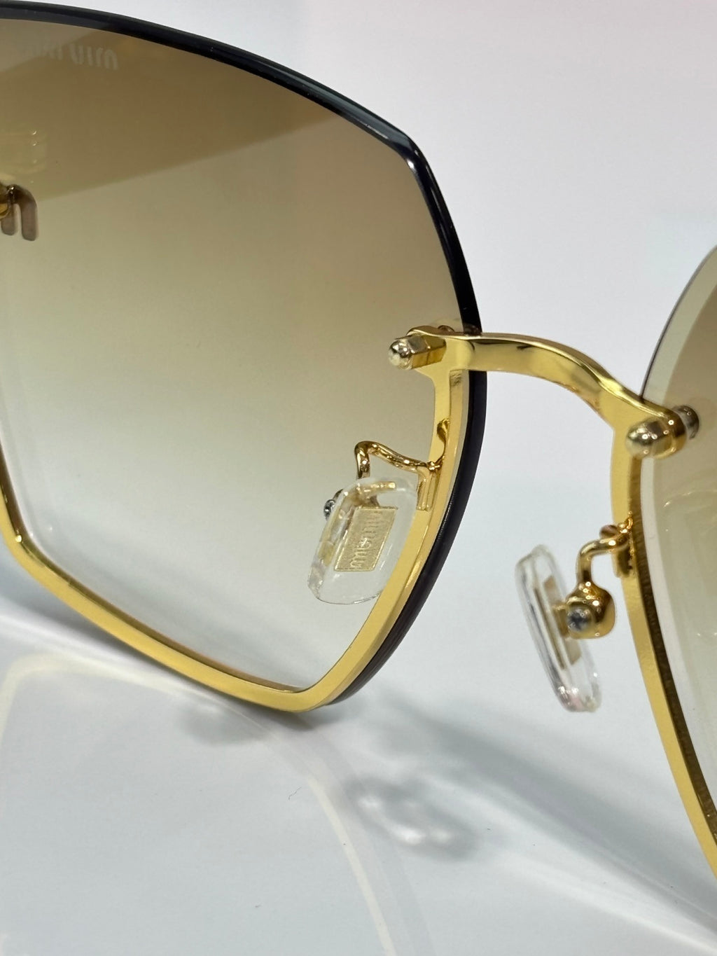 MiuMiu cat-eye sunglasses close-up of gold-tone frame and clear tinted lenses