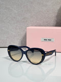 MiuMiu black round sunglasses with gold logo temples and dark lenses
