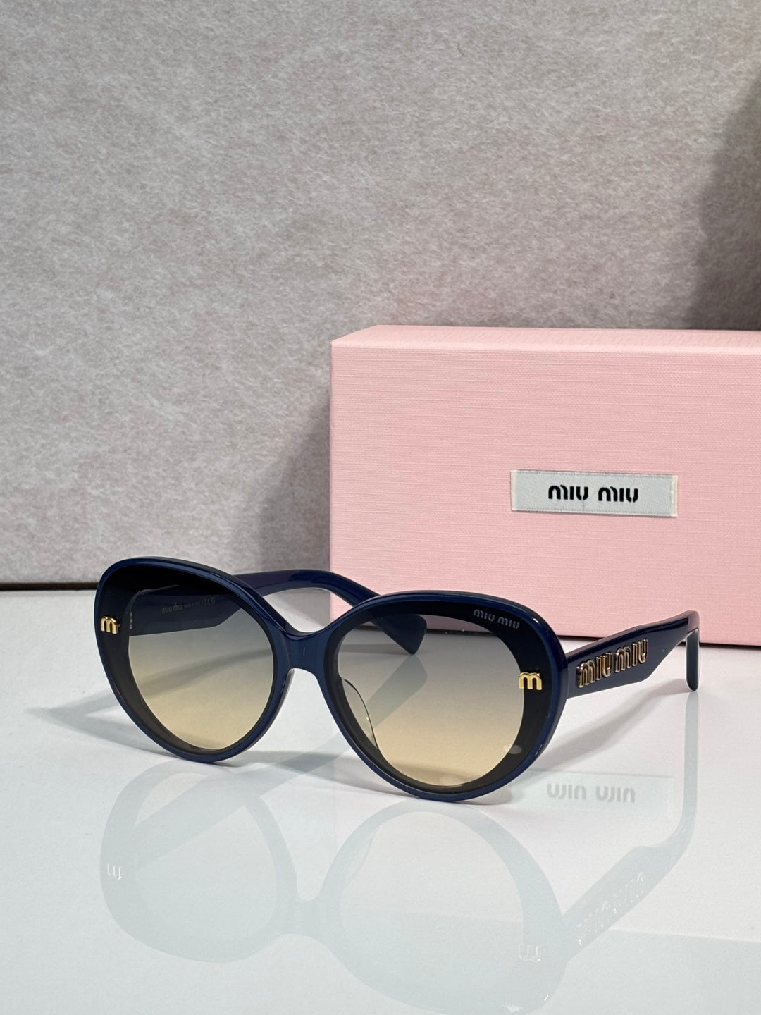 MiuMiu black round sunglasses with gold logo temples and dark lenses