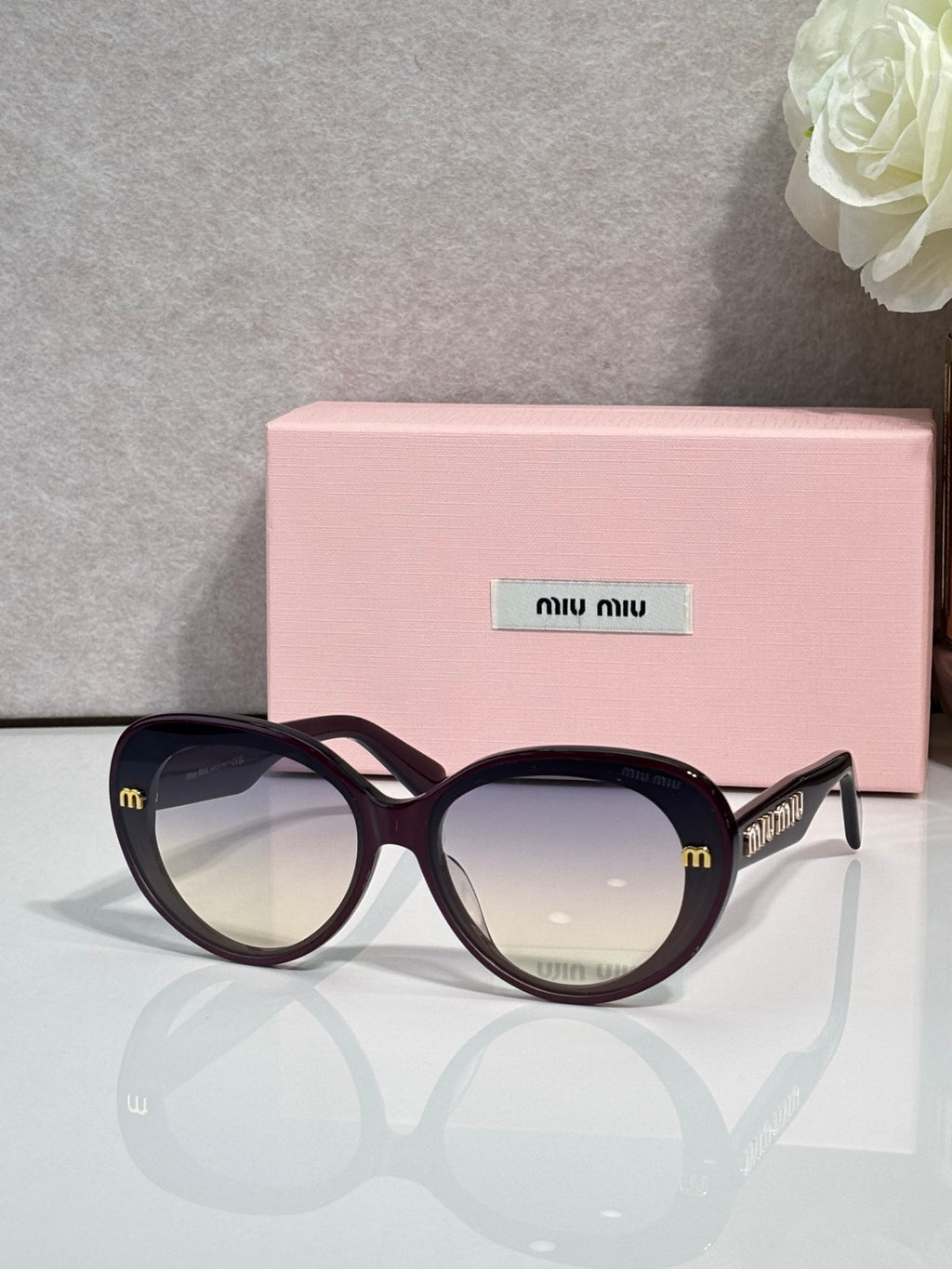 MiuMiu black round sunglasses with gold logo temples and mirrored dark lenses