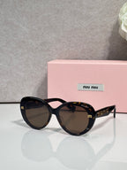 MiuMiu black round sunglasses with tortoise patterned arms and dark lenses