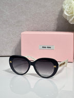 MiuMiu black round sunglasses with gold logo detail on temples and dark lenses