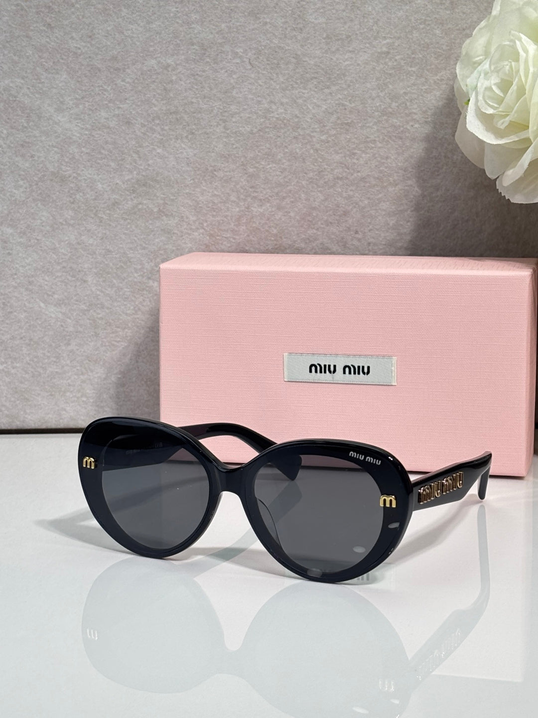 MiuMiu black round sunglasses with gold logo temples and dark gradient lenses