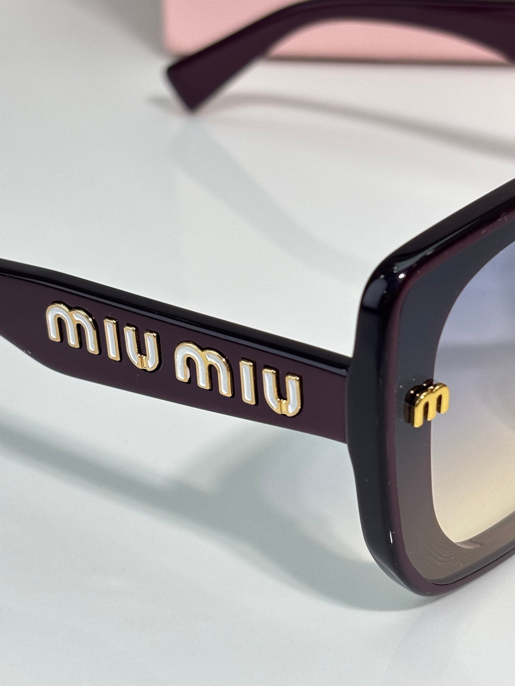 Black sunglasses temple with gold “miu miu” logo detail