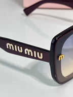 Black sunglasses temple with gold “miu miu” logo detail