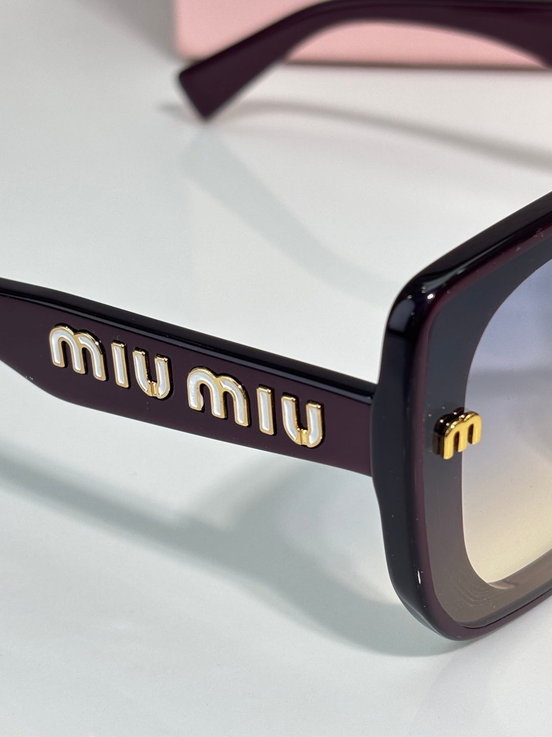 Black sunglasses temple with gold “miu miu” logo detail