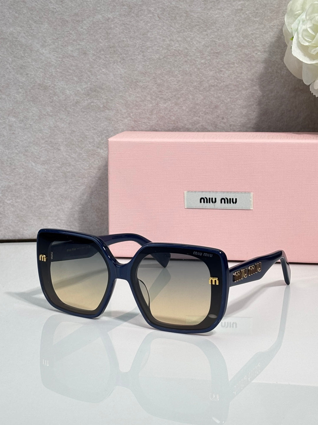 Square sunglasses with navy blue frames and yellow-gold logo
