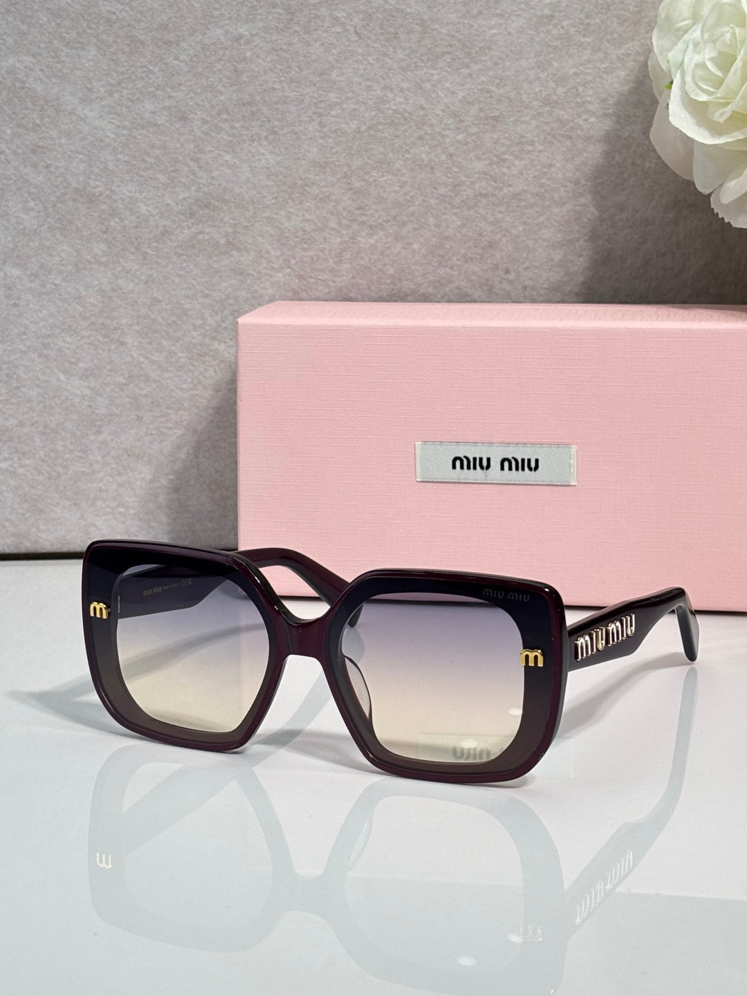 Square sunglasses with dark frames and clear logo accents on temples