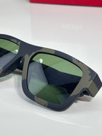 Camo sunglasses side close-up with green lenses and Prada red logo on arm.