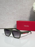 Black camo sunglasses with green lenses and Prada logo on temple.
