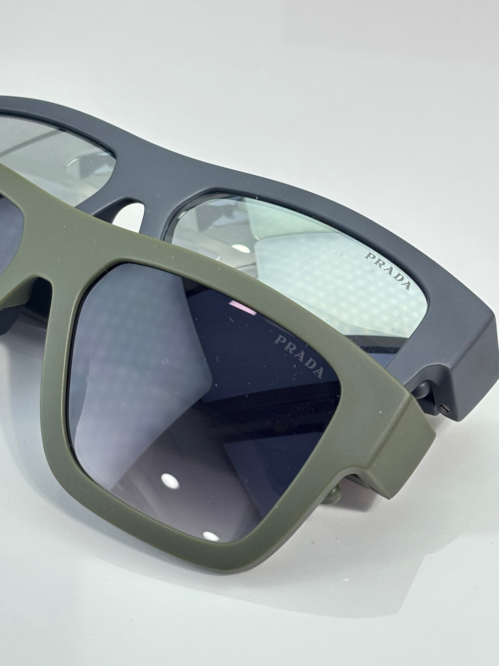 Camo sunglasses close-up: dark lenses with Prada marking on arm.