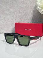 Dark blue camo sunglasses with green lenses and red Prada logo stripe.