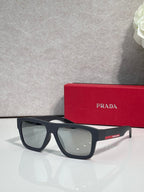 Black camo sunglasses with green lenses and Prada logo on arm.