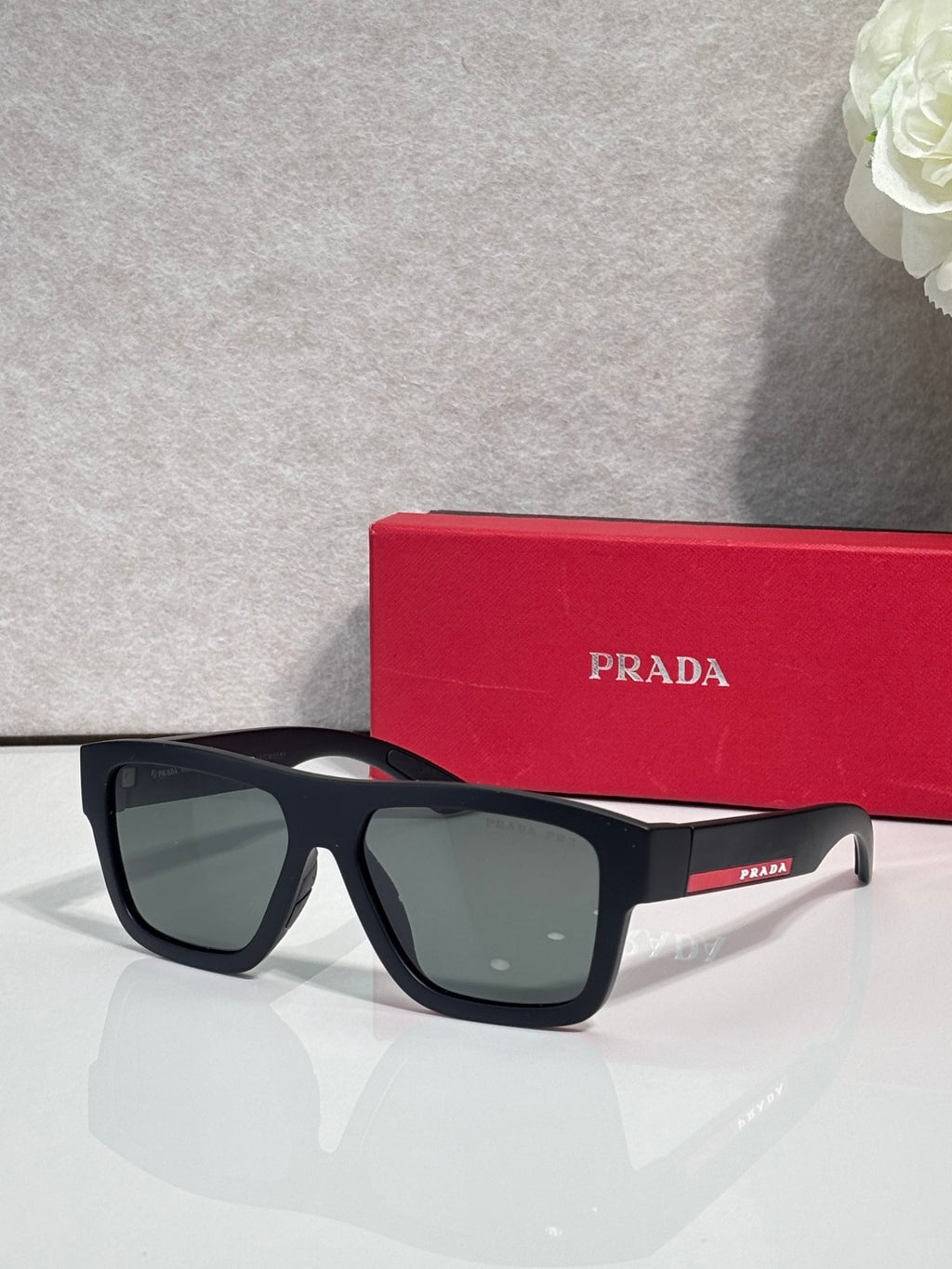 Matte black camo sunglasses with dark green lenses, front view with Prada.