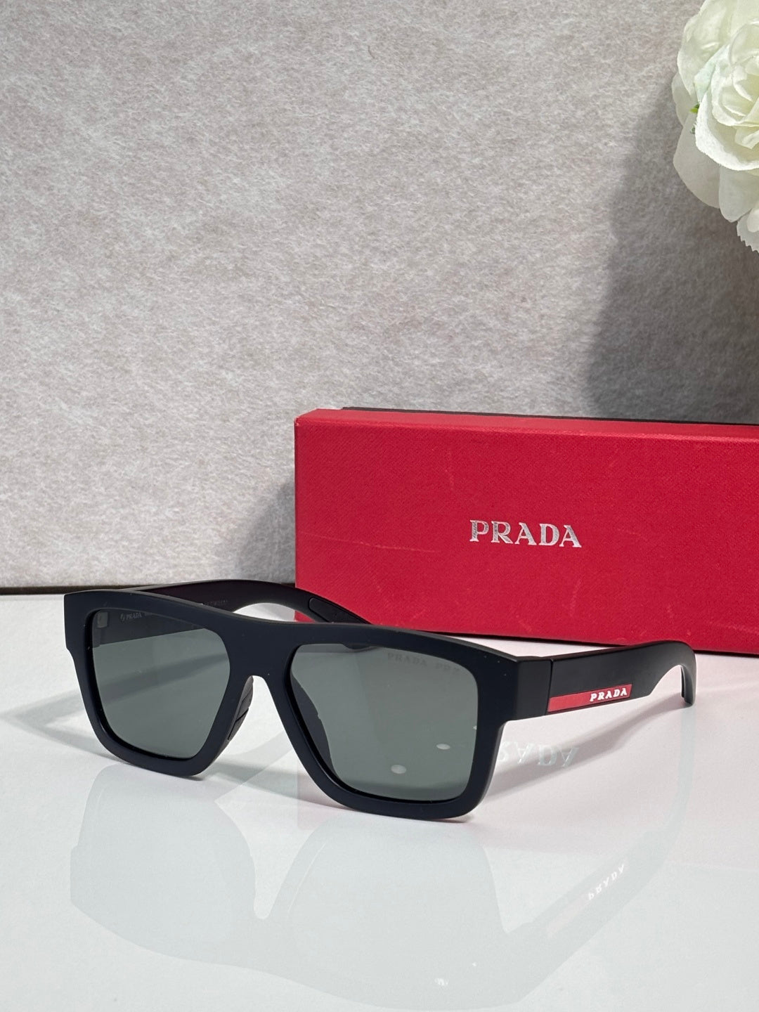 Matte black camo sunglasses with dark green lenses, front view with Prada.