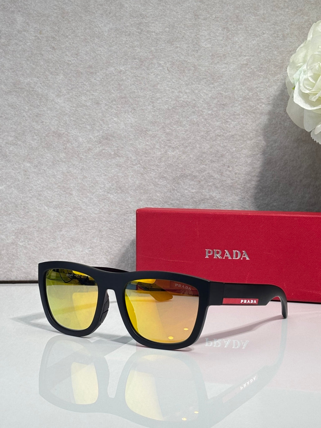 Prada sunglasses with black frames and yellow-tinted lenses, PRADA logo at temple