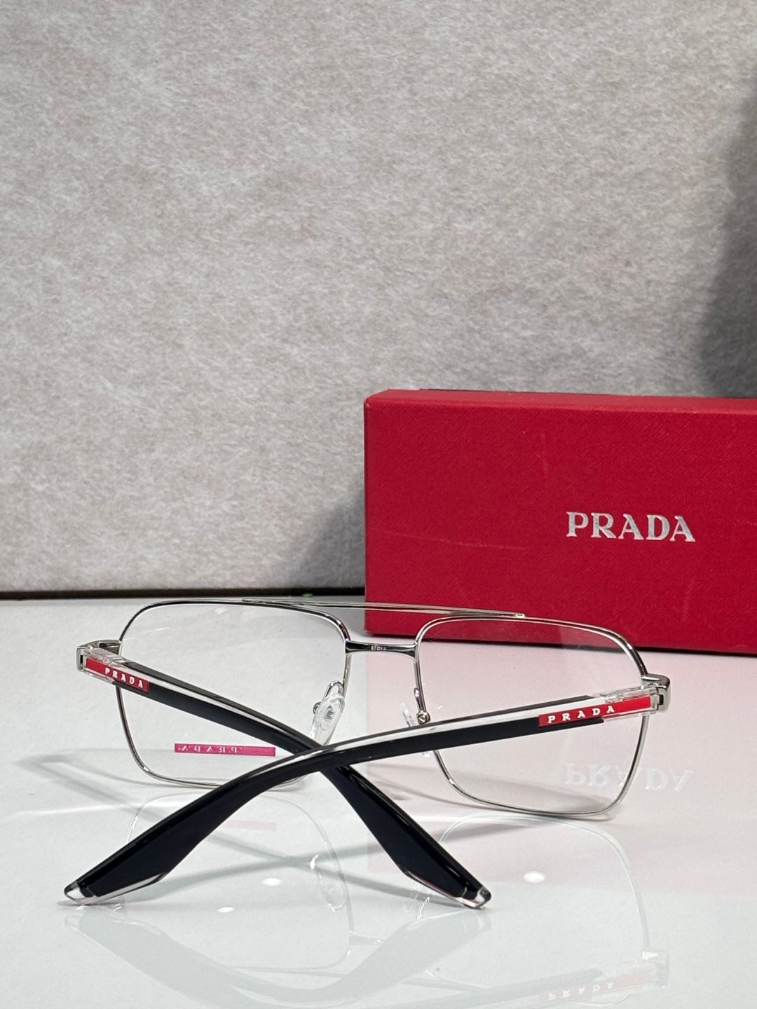 Prada eyeglasses with clear lenses and slim metal frame, black temple arms with logo.