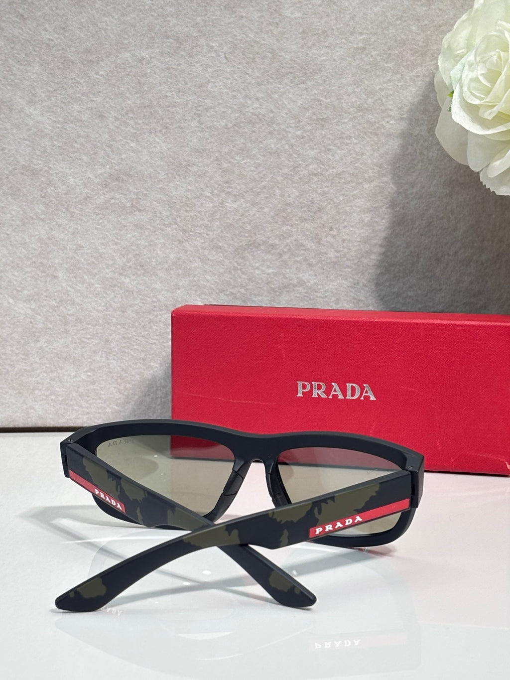 Prada sunglasses with black angular frames and green-tinted lenses