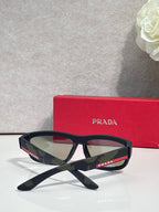 Prada sunglasses with black angular frames and green-tinted lenses