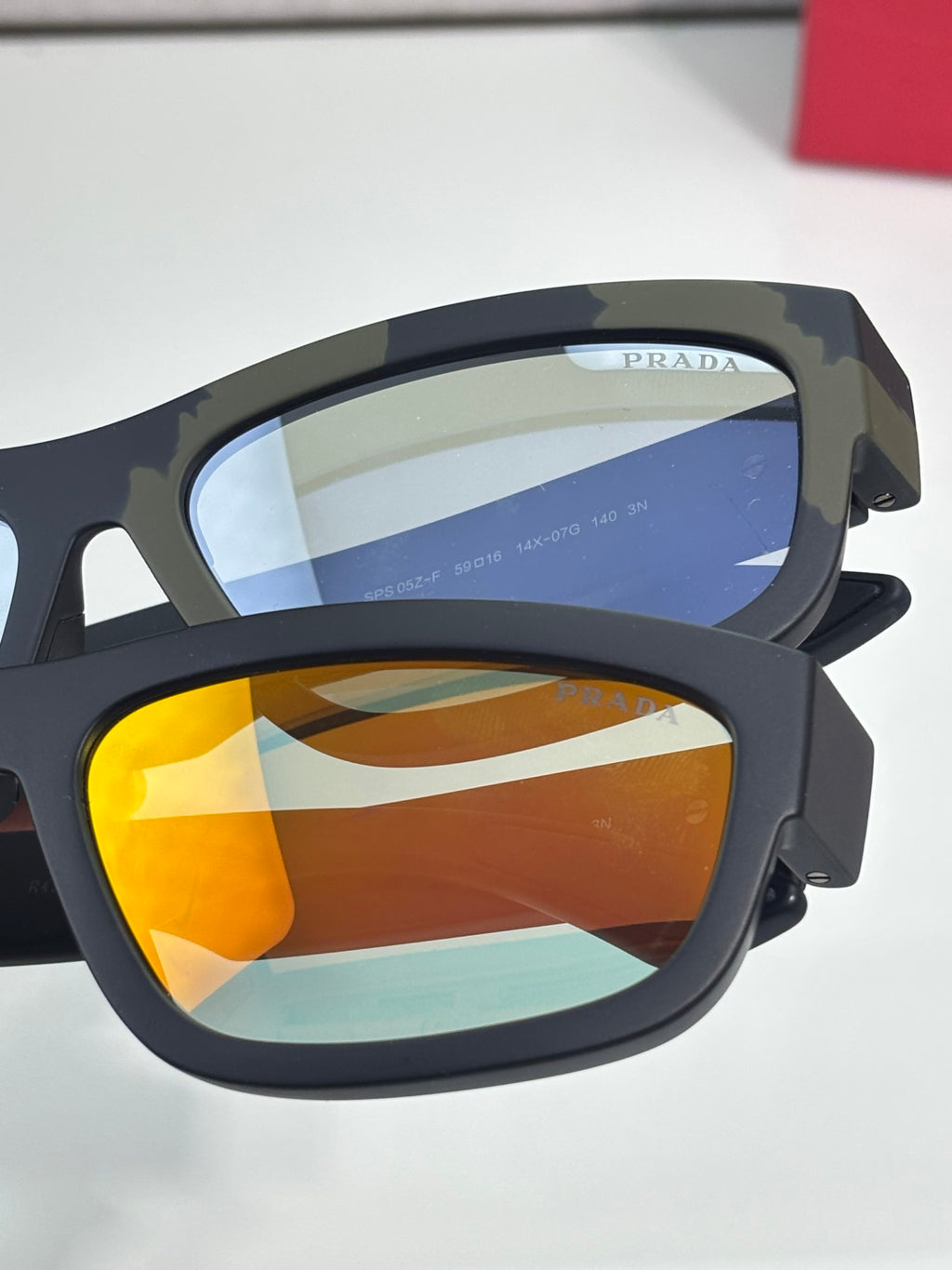 Prada sunglasses close-up with dark mottled frame and blue and orange lenses