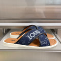 Blue Louis Vuitton slide sandals with monogram straps and tan leather footbed
