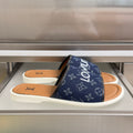 Louis Vuitton slide sandals in navy monogram with white sole and tan footbed