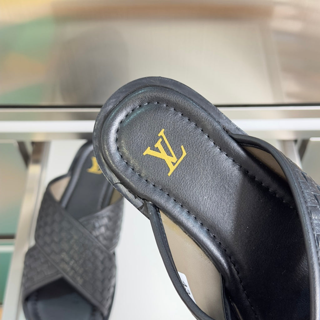 Louis Vuitton black leather slide sandal close-up of gold LV emblem on strap