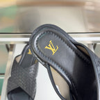 Louis Vuitton black leather slide sandal close-up of gold LV emblem on strap