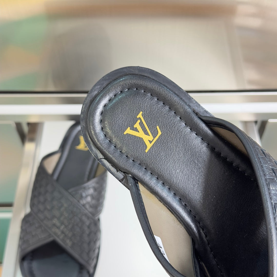 Louis Vuitton black leather slide sandal close-up of gold LV emblem on strap