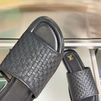Black woven leather slide sandals with thick padded straps and smooth outsole