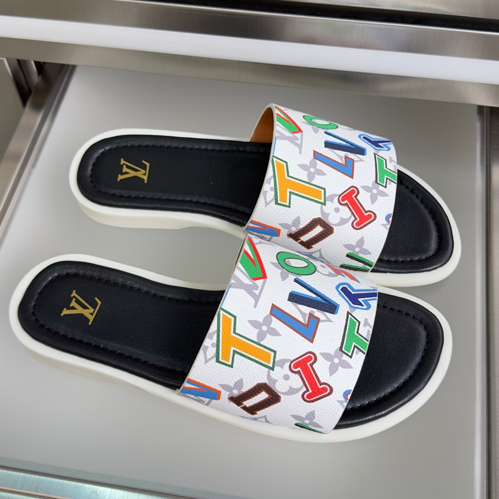 Black slide sandals with a white strap covered in multicolor monogram graphics