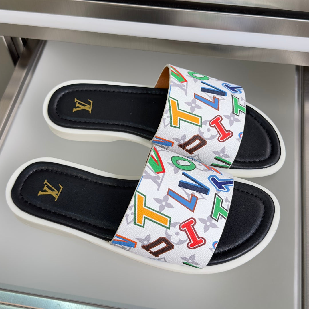 Black slide sandals with a white strap covered in multicolor monogram graphics
