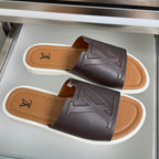 Pair of dark brown leather slide sandals with white soles and Louis Vuitton monogram