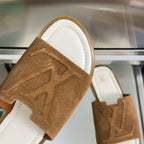 Brown suede slide sandal strap detail with LV monogram and stitched edges.