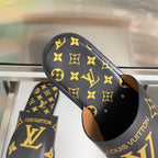 Black slide sandals with gold monogram pattern and tan interior lining