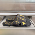 Black slide sandals with gold Louis Vuitton monogram and flower logo straps
