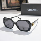 Chanel sunglasses, black frames, dark tinted lenses, gold logo detail.