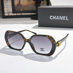 Chanel sunglasses, dark tortoiseshell frames, purple-tinted lenses, gold logo detail.