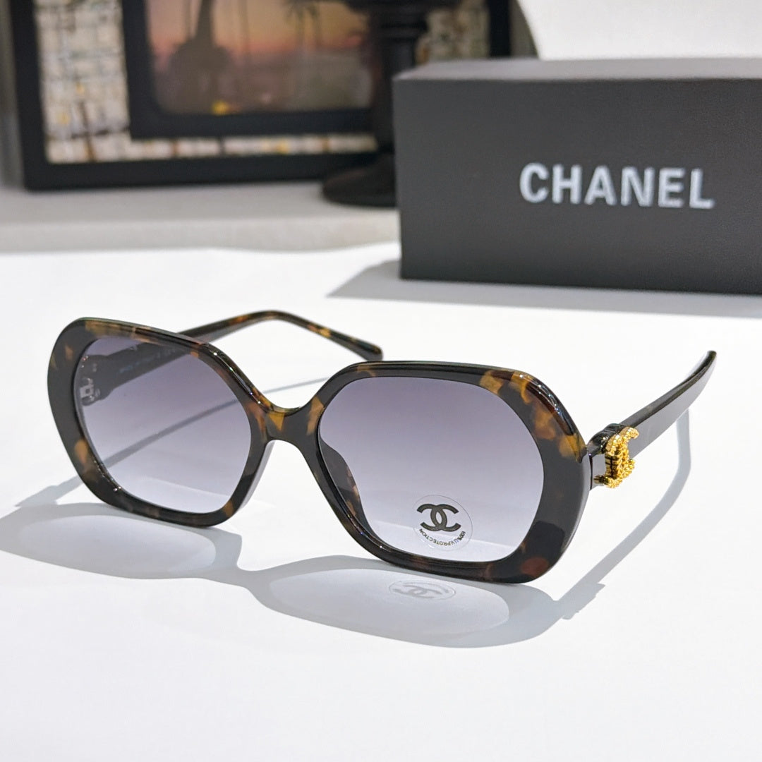 Chanel sunglasses, dark tortoiseshell frames, purple-tinted lenses, gold logo detail.