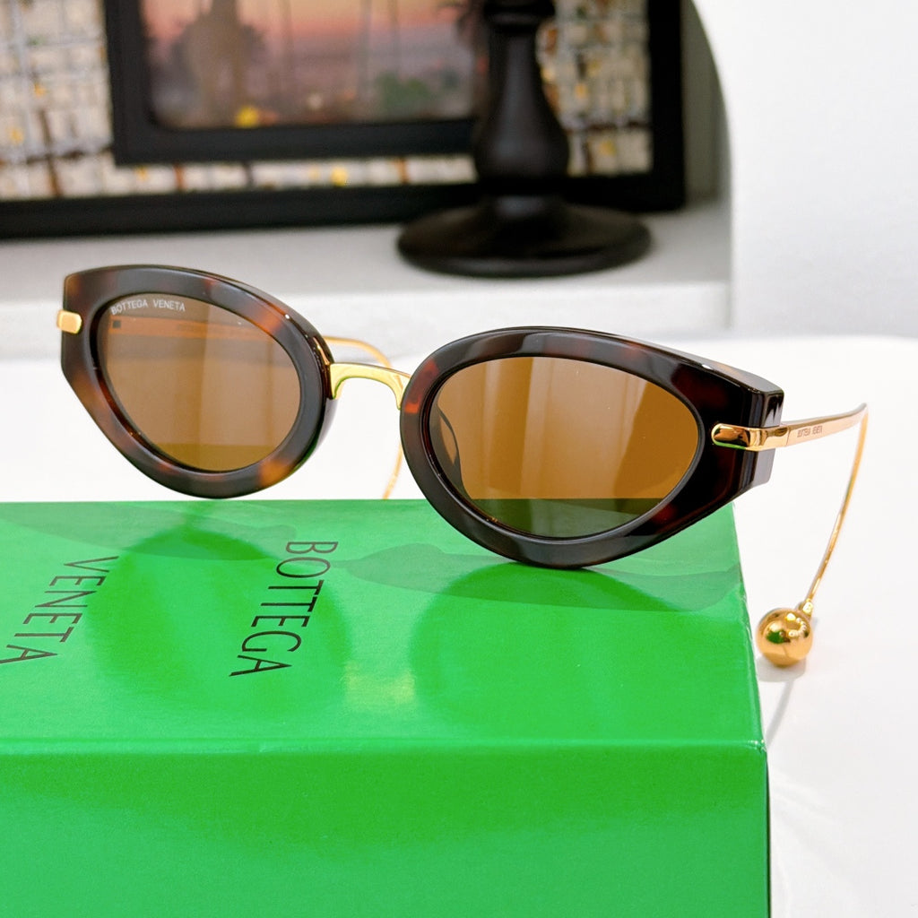 Bottega Veneta glasses with dark frames and warm amber tinted lenses, gold-tone accents