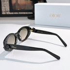Black oval sunglasses, side view, with gold hinge detail and logo band on arm