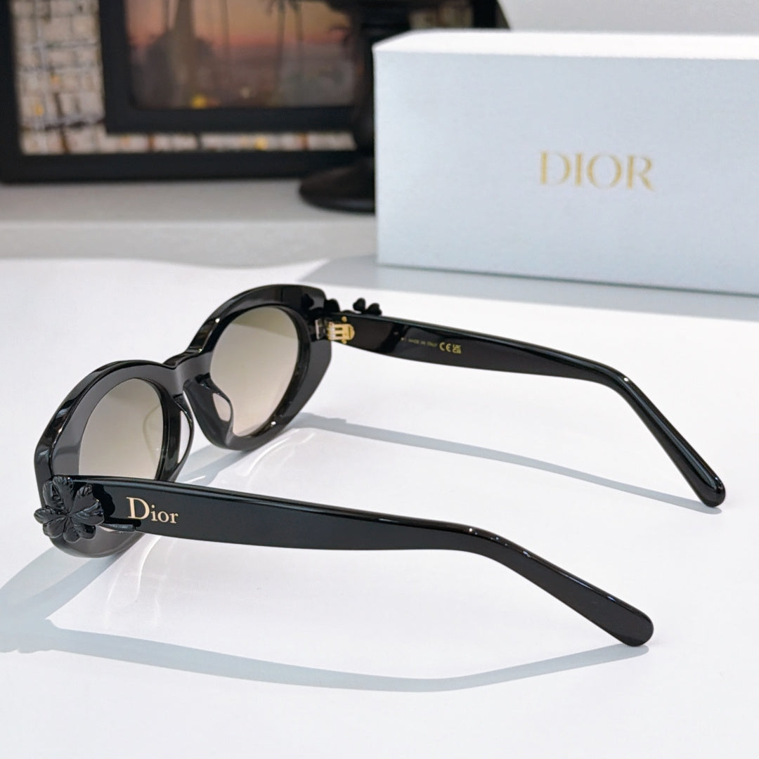 Black oval sunglasses, side view, with gold hinge detail and logo band on arm
