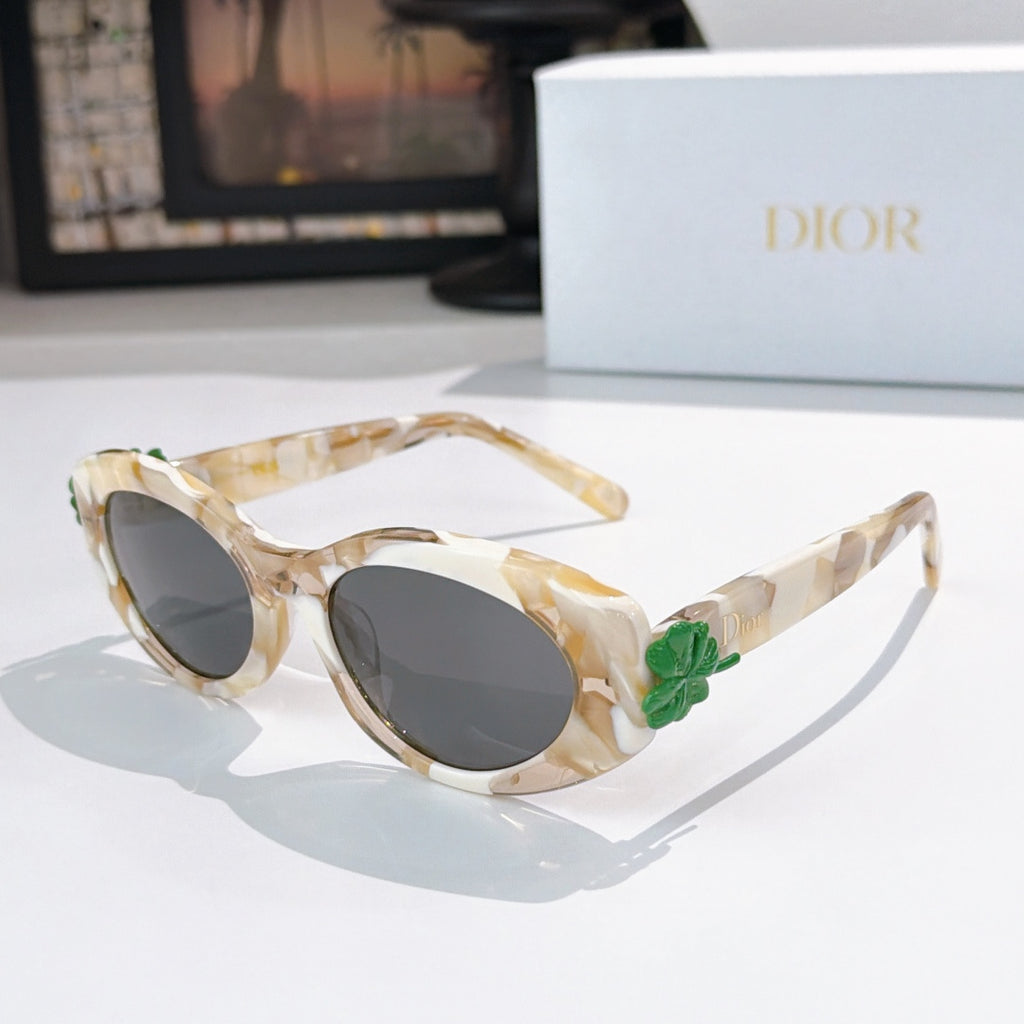 Ivory marbled oval sunglasses with dark lenses and green floral charm on arm