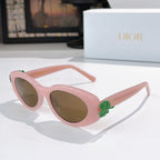 Light pink oval sunglasses with brown lenses and green floral charm on arm