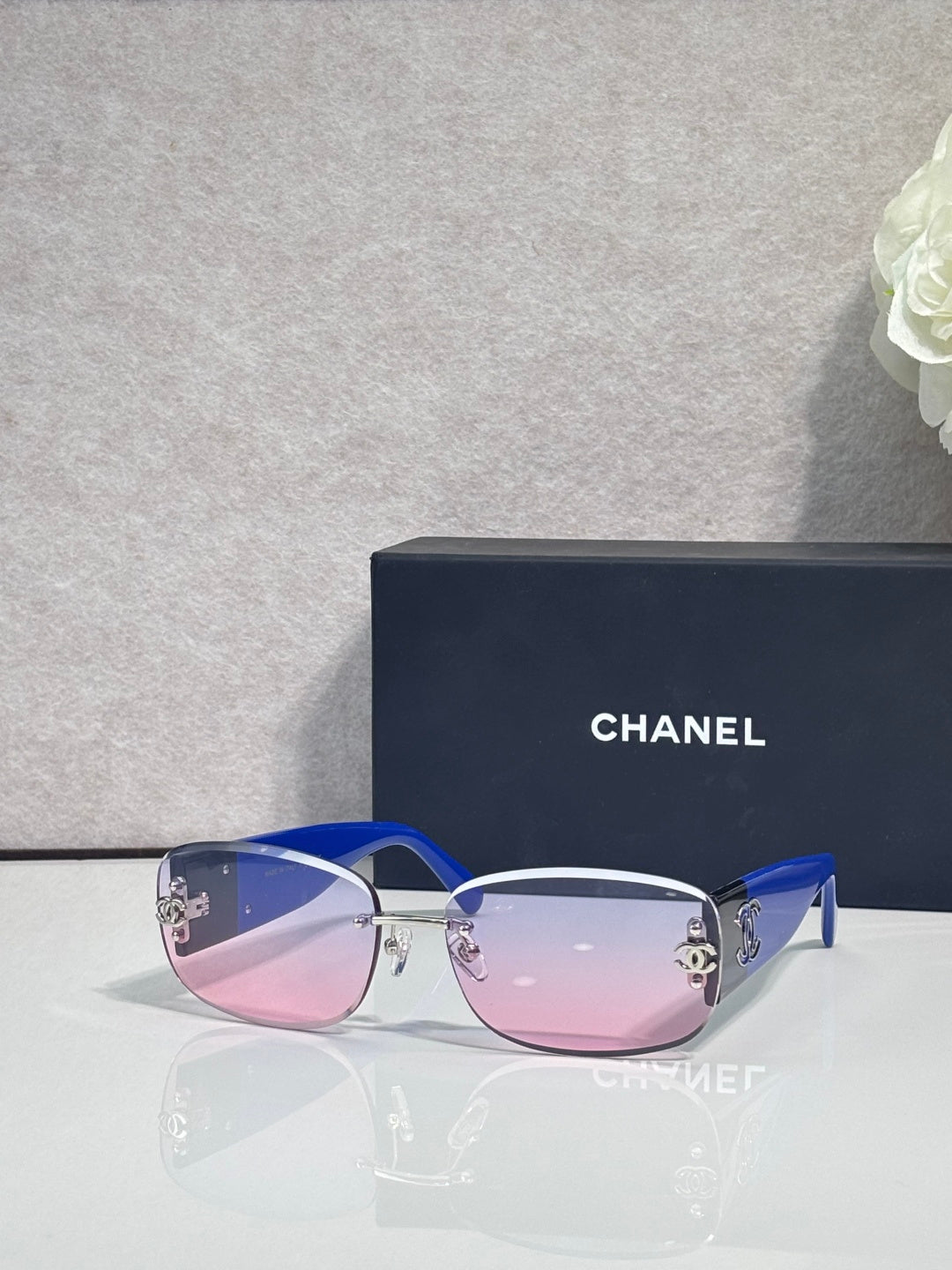 Blue-accent sunglasses with pink-tinted lenses and side logo detail, metal temples
