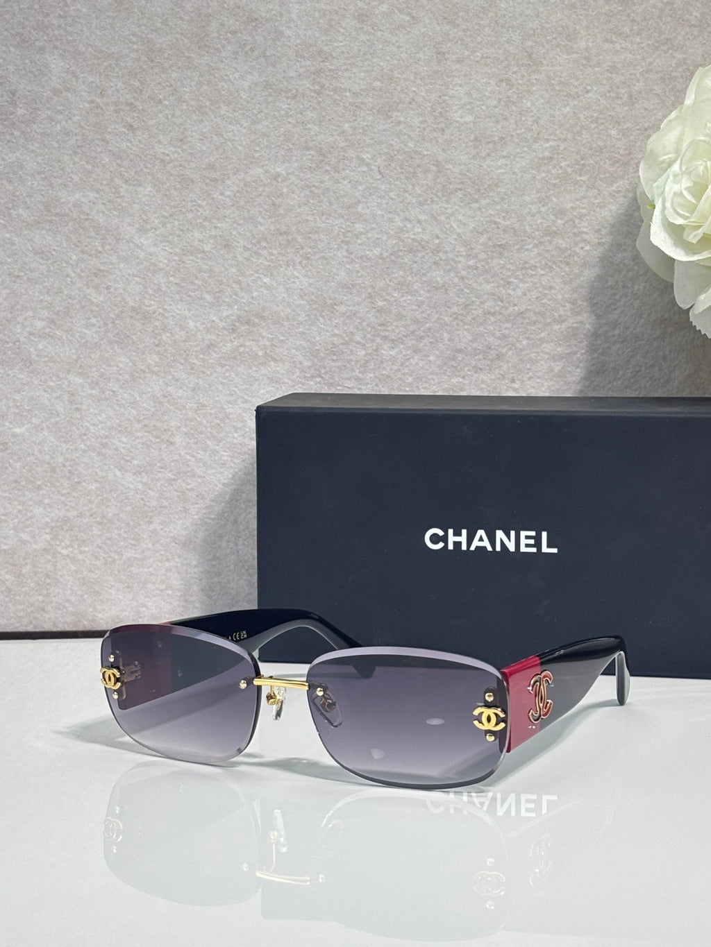 Gold-framed sunglasses with dark blue tinted lenses and side logo detail, metal temples