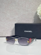 Gold-framed sunglasses with dark blue tinted lenses and side logo detail, metal temples